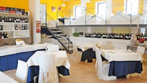 Un restaurant doté de plusieurs tables, d’un présentoir à vin et d’un escalier.