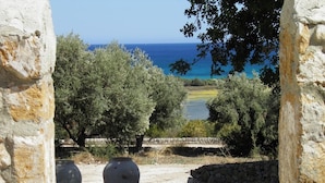 Un mur de pierre offrant une vue sur la mer et les oliviers.