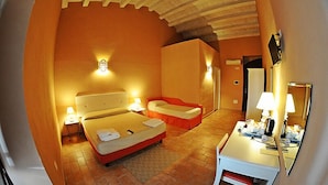 Une chambre d’hôtel comprenant un lit, des tables de chevet, un bureau avec un miroir et un petit coin salon.