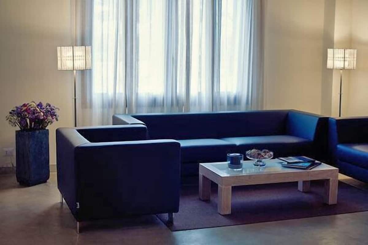 A modern living room with a dark blue sofa, a wooden coffee table, and two floor lamps.