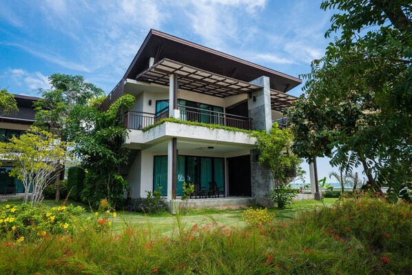 A modern two-story house with a covered balcony, surrounded by lush greenery and flowering plants. - i Tara Resort & Spa (Ban Laem)