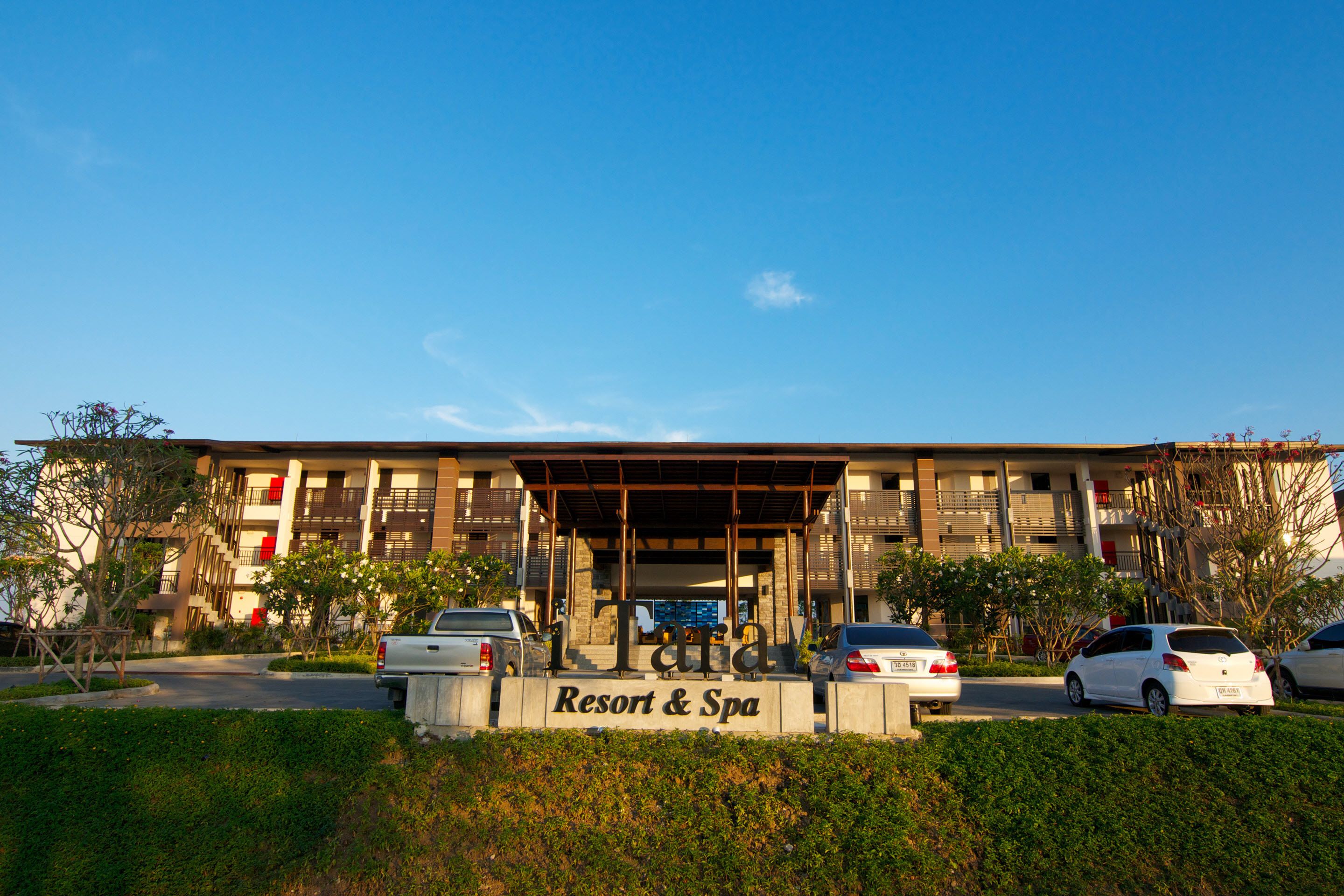 Un edificio con un cartel que dice "Resort & Spa" y varios coches aparcados delante.
