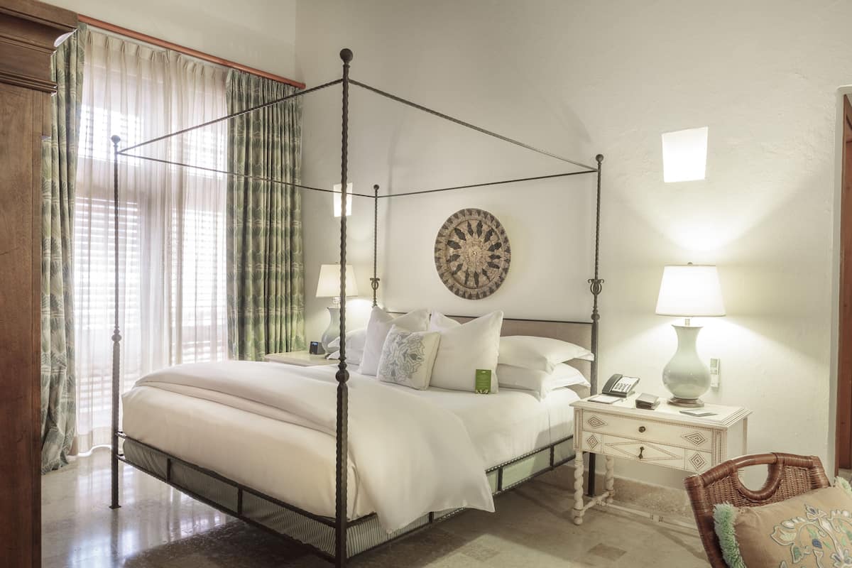 Un letto a baldacchino con un comodino, una lampada e un elemento decorativo a parete.