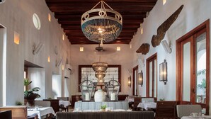 A dining area with a chandelier, wooden ceiling, and tables set for dining.