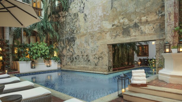 A pool area with lounge chairs and a stone wall.
