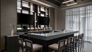 Una cocina moderna con una isla grande, taburetes de bar, un televisor de pantalla plana y un refrigerador para vinos.