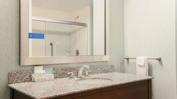 A bathroom with a granite countertop, a sink, a mirror, and a towel rack.