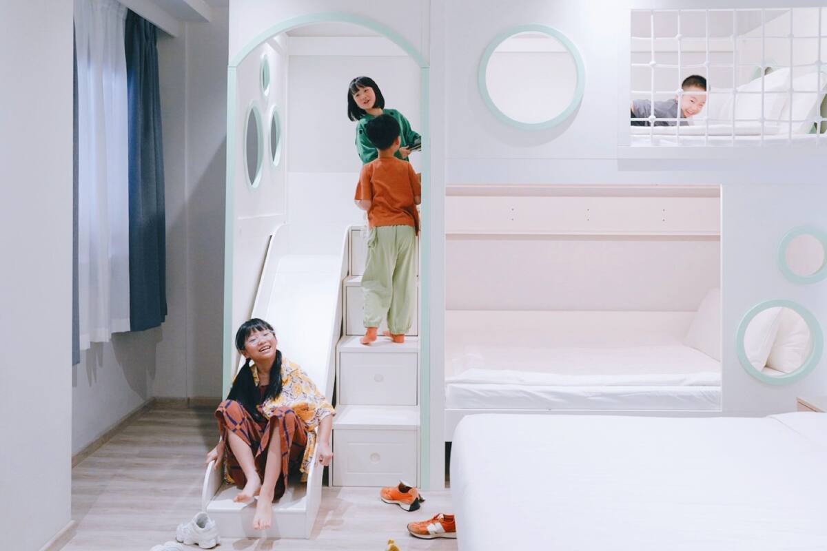 A modern bedroom with a bunk bed, a small staircase, and a mirror.