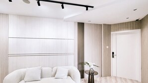 Una habitación moderna con un sofá blanco, suelo de madera y una puerta con persianas verticales.