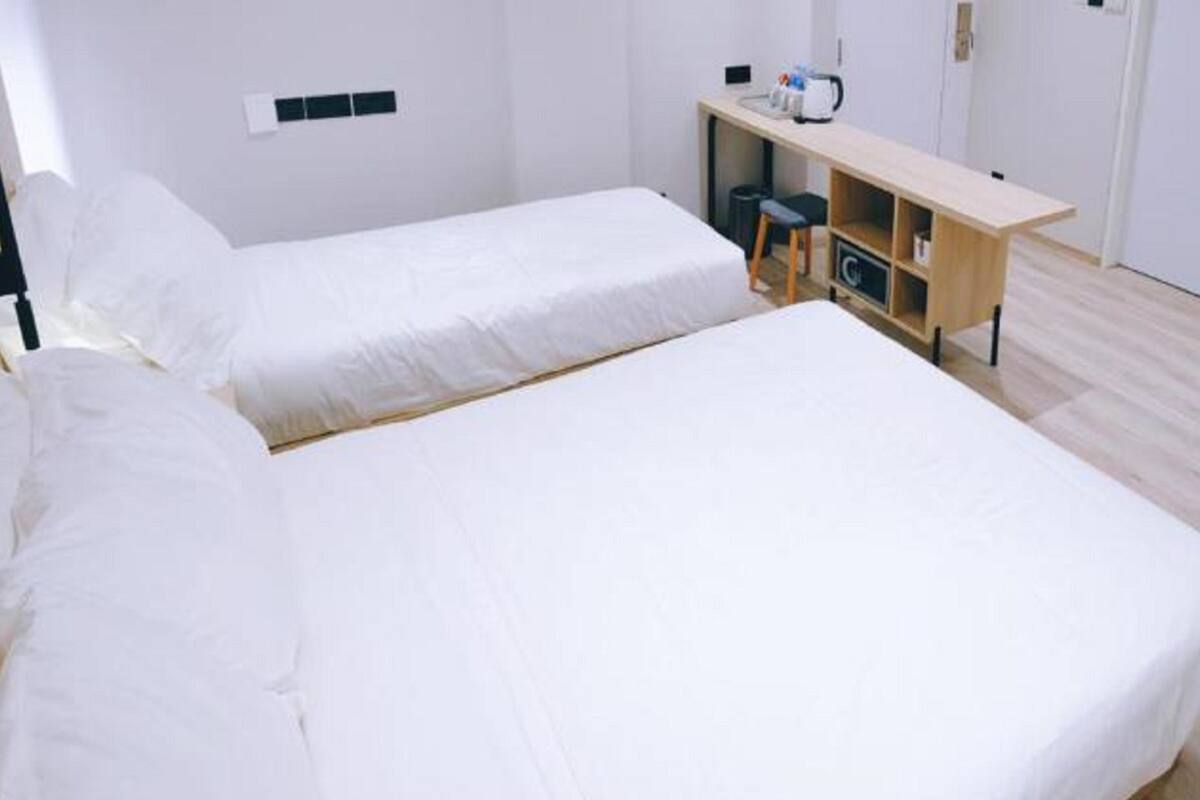 A hotel room with two beds, a desk with a computer, and a wardrobe.