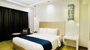 A hotel room with a large bed, a chair, a bedside table, and a decorative wall panel. - Holiday Inn Amritsar Ranjit Avenue by IHG (Amritsar)