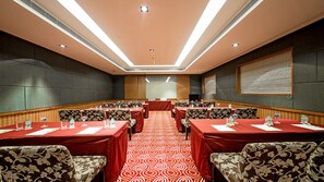 Une salle de conférence avec une longue table, de nombreuses chaises et un sol recouvert de moquette.