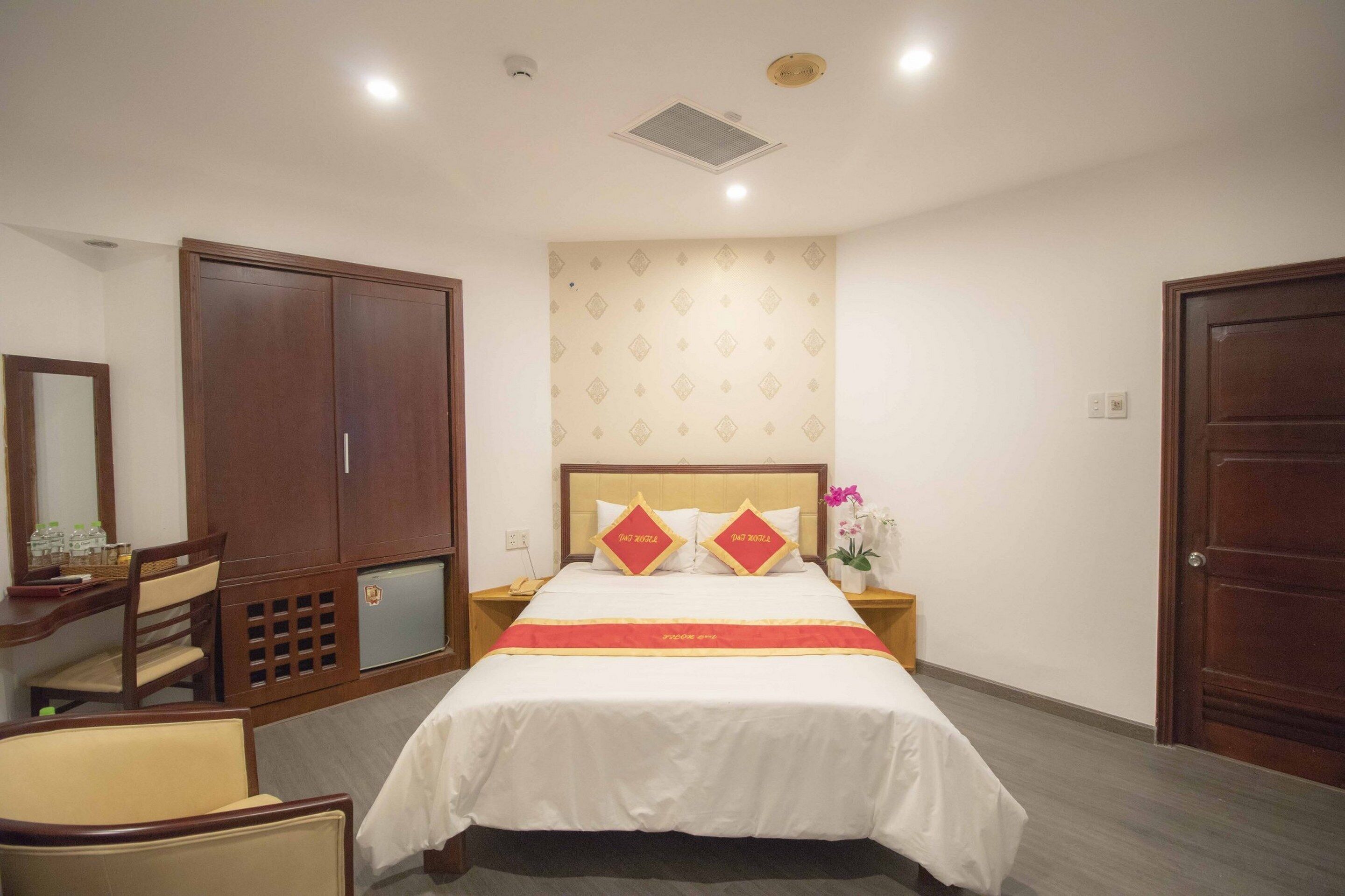 Een hotelkamer met een groot bed, een kledingkast, een bureau met stoel en een kleine koelkast.