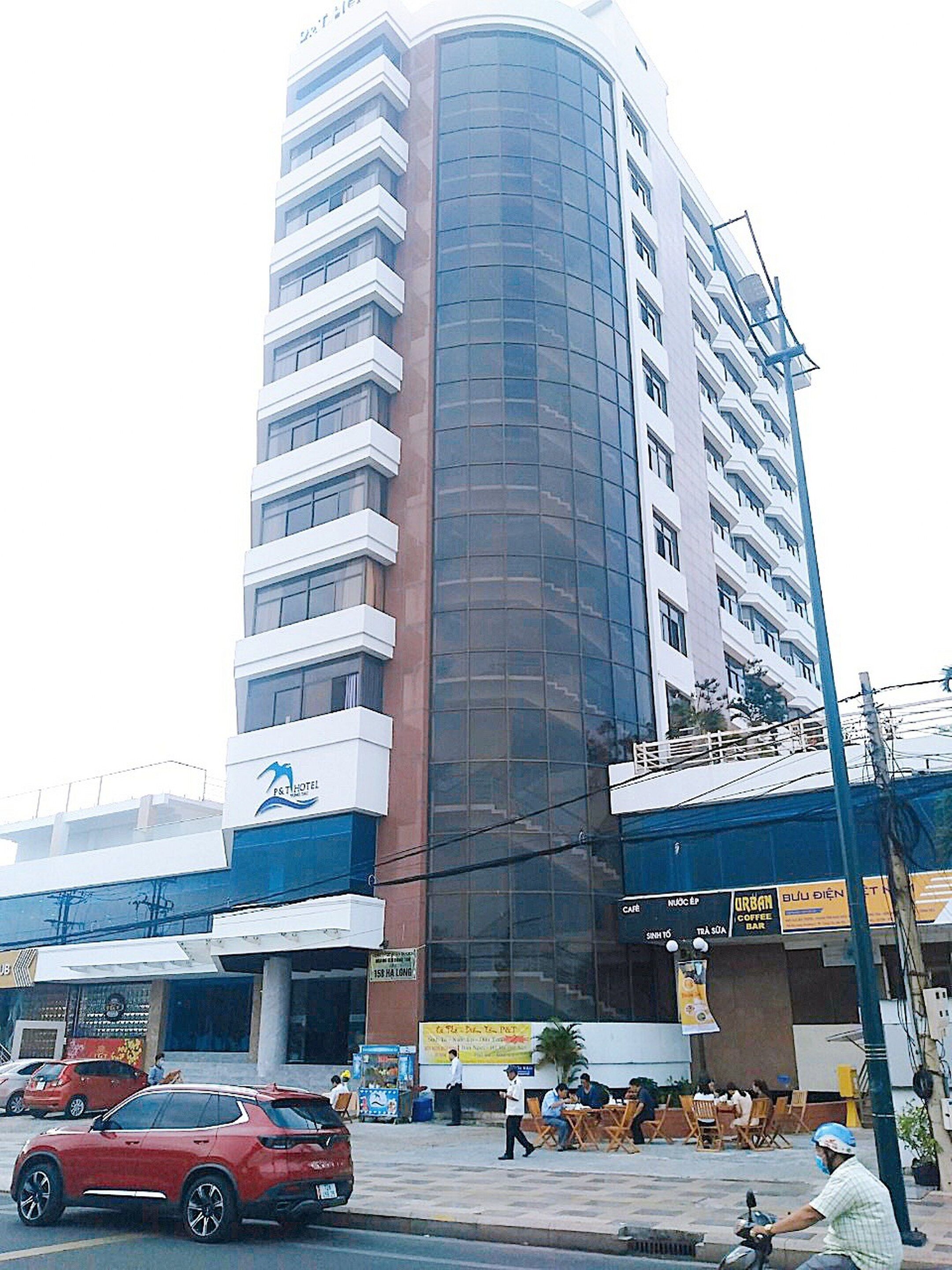 A multi-story building with a modern design, featuring a prominent glass facade and a mix of white and brown exterior.