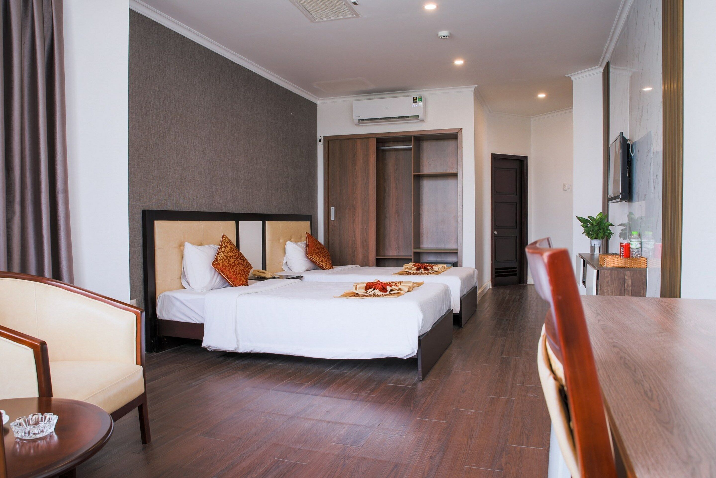 Una habitación de hotel con una cama, mesitas de noche, un televisor y un armario.