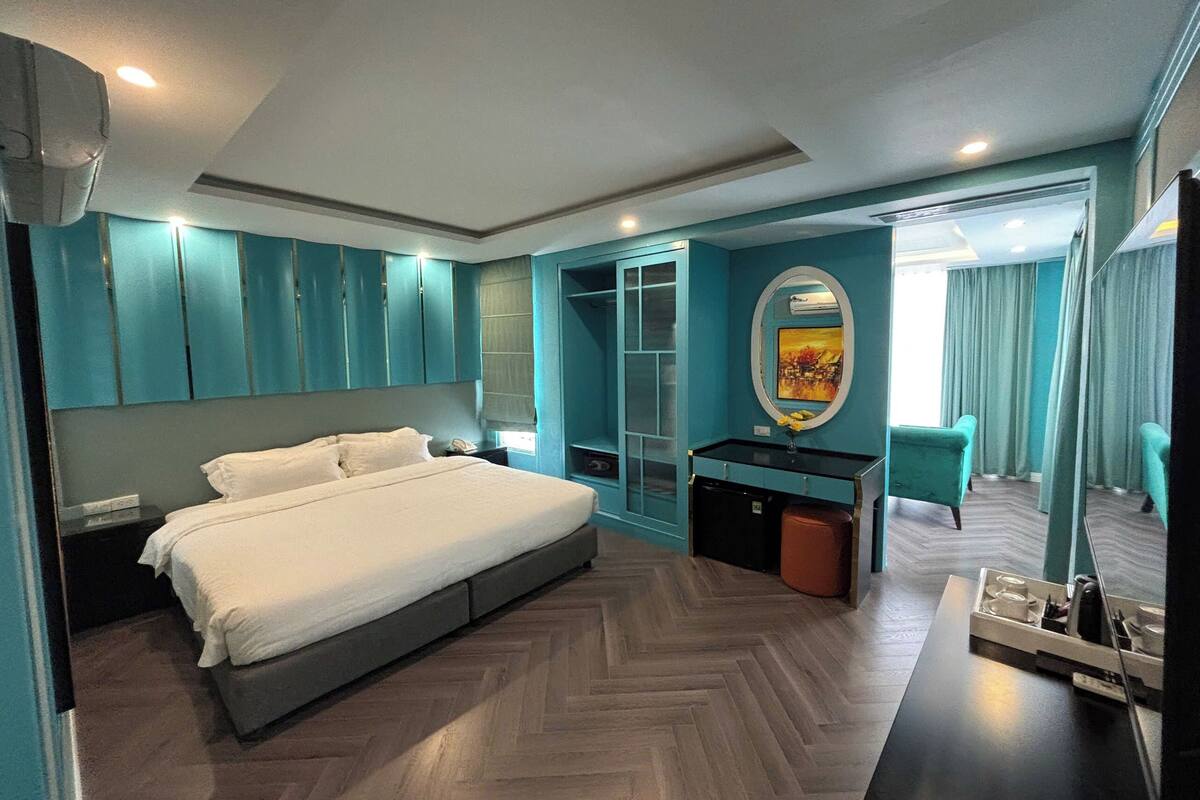 Une chambre d’hôtel moderne avec un grand lit, un bureau doté d’un miroir et donnant sur le couloir.