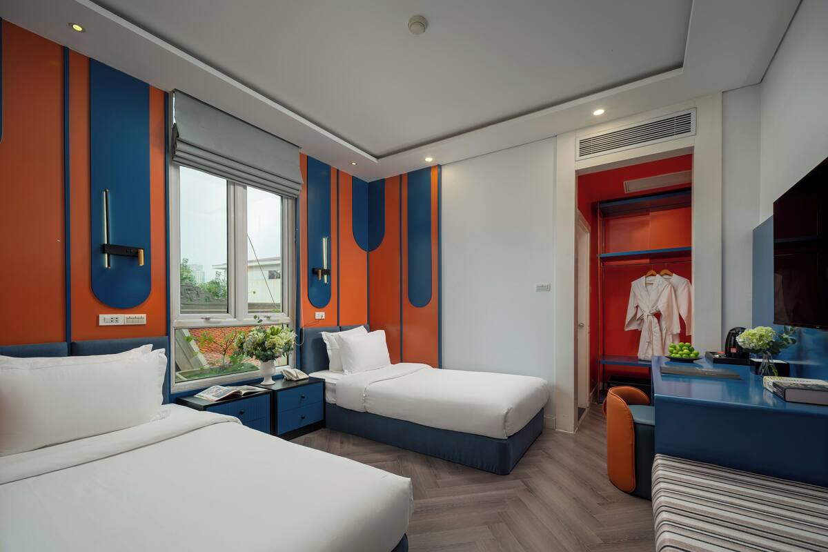 Une chambre d’hôtel moderne équipée de deux lits, d’un bureau et d’un coin salon.