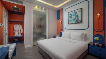 A modern bedroom with a large bed, a walk-in closet, and a bathroom with a glass door.