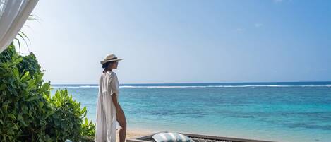 A person standing by a pool with a view of the ocean.