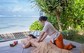 A massage therapy session on a beach with a view of the ocean.