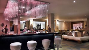 A bar area with stools, a counter with bottles, and a seating area with couches and a sofa.