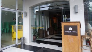 The entrance to Grande Vista Hotel with a glass door, a signboard, and a reception area visible inside.