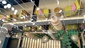 A hotel lobby with a high ceiling decorated with hanging lanterns and a patterned ceiling.