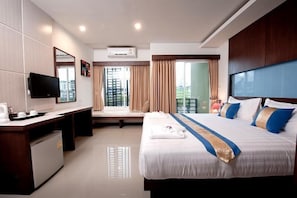 A hotel room with a bed, a desk, a television, and a window with curtains.