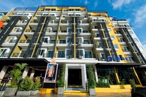 Un hotel de varios pisos con balcones, una entrada central y un letrero que dice "BLUE SKY".