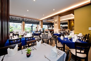 A restaurant with multiple tables set for dining, featuring blue tablecloths and white napkins.