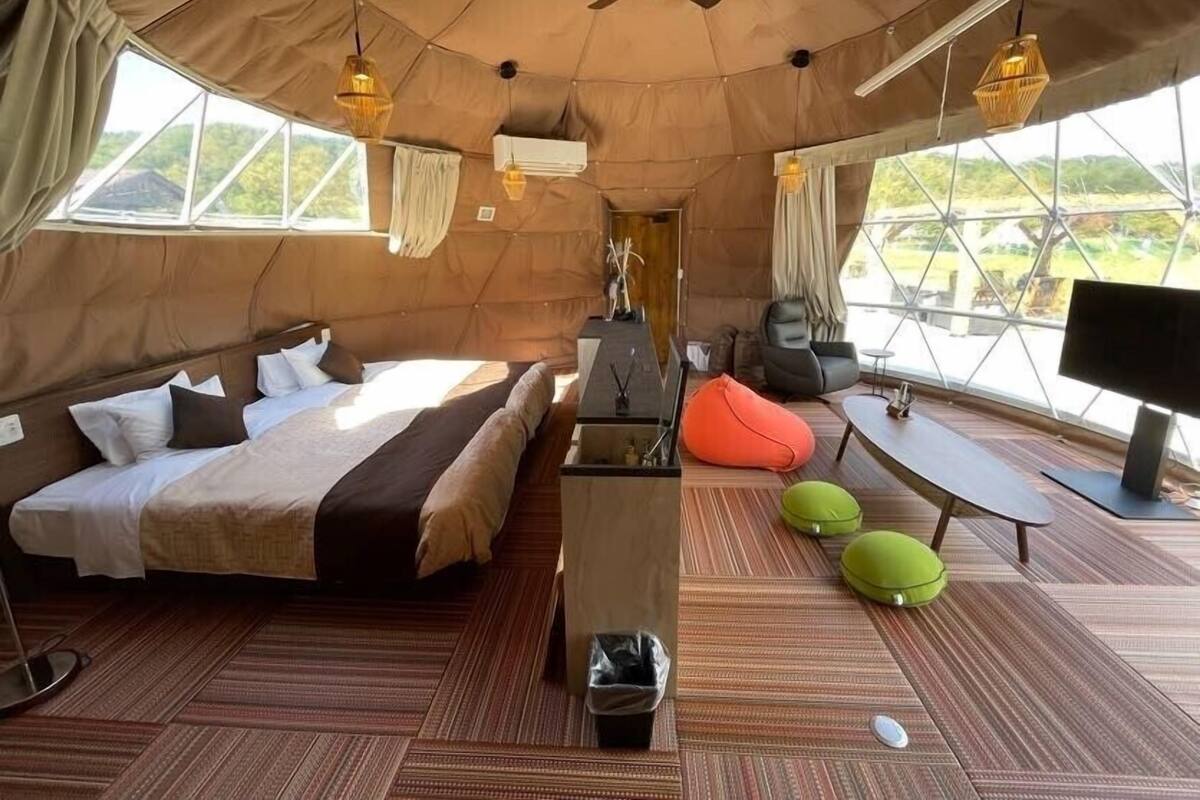A spacious tent with a bed, seating area, and a TV.