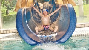 A child sliding down a water slide at a poolside area. - LiVEMAX RESORT Greenpia Onuma (Mori)