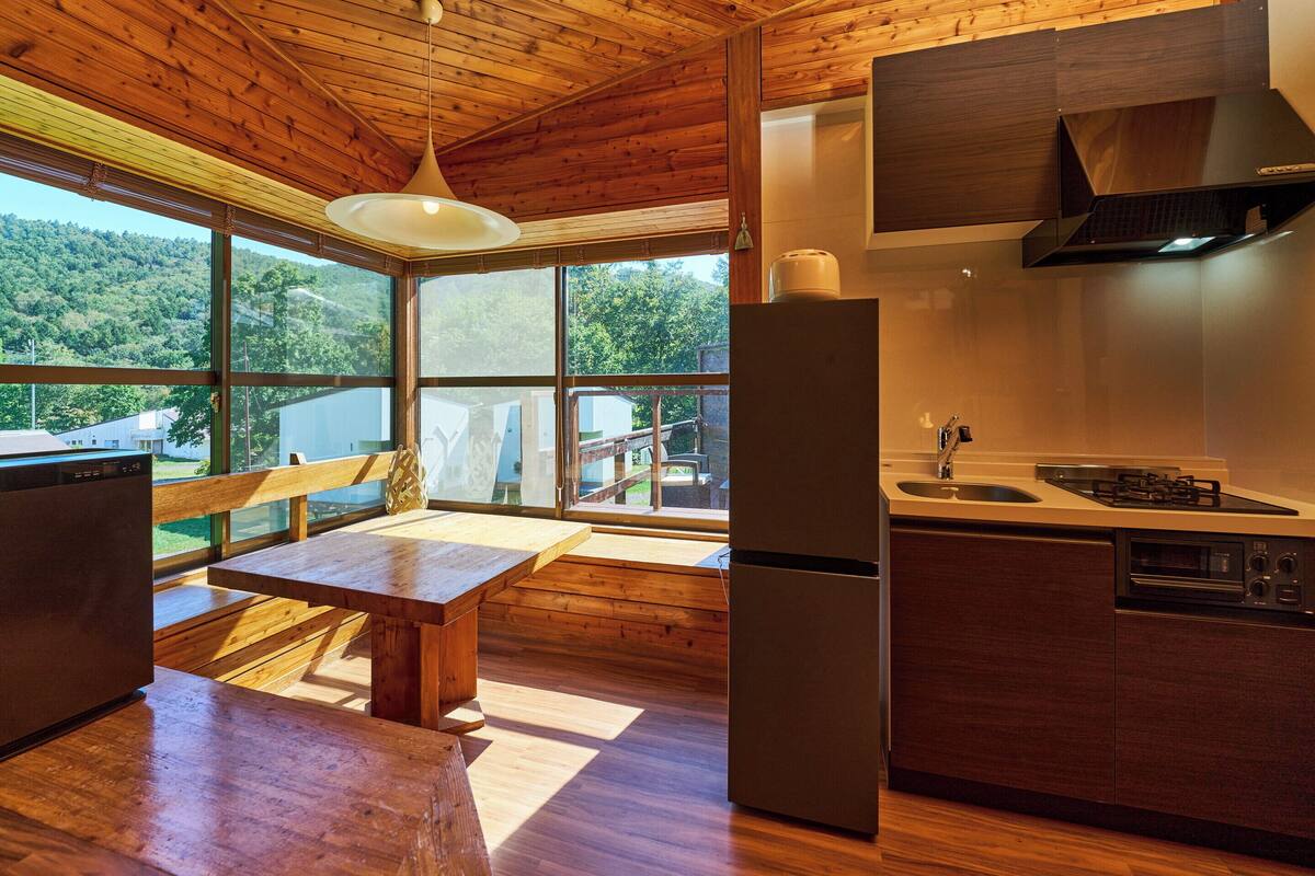 A modern kitchen with a large window, wooden ceiling, and a built-in stove.