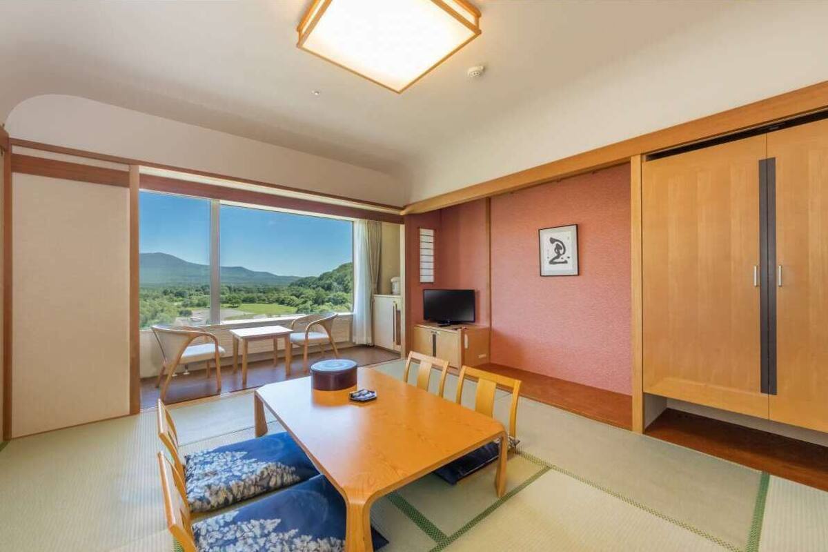 A room with a dining table, chairs, a television, and a wardrobe.