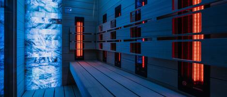 A sauna with wooden benches and red light panels.