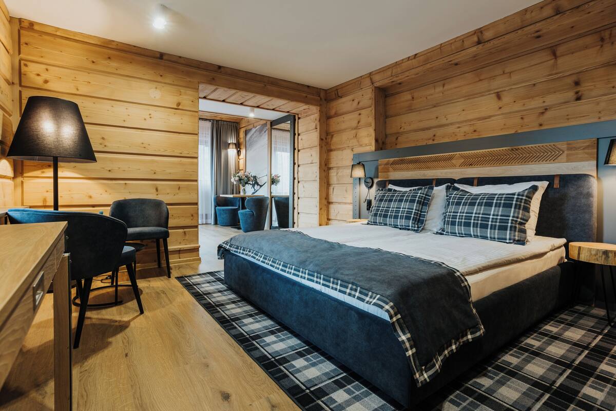 A wooden-paneled room with a bed, a desk, and a chair.