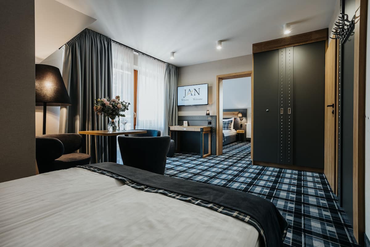 A hotel room with a bed, a desk, a chair, a TV, and a wardrobe.