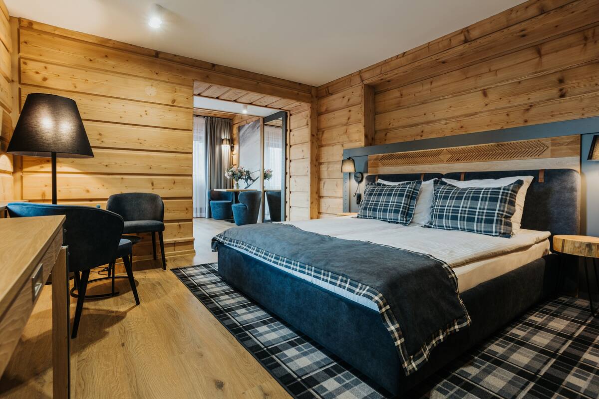 A wooden-paneled room with a bed, a desk, and a chair.
