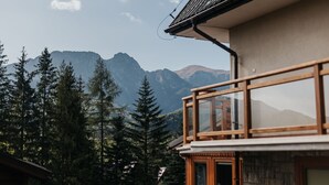 A mountain view from a balcony with a wooden railing, surrounded by evergreen trees. - Apartamenty Jan (Zakopane)