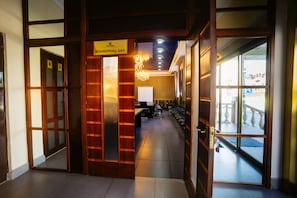 A hotel lobby with a reception desk, a chandelier, and a view of the Grand Hotel. - Grand Hotel (Bishkek)