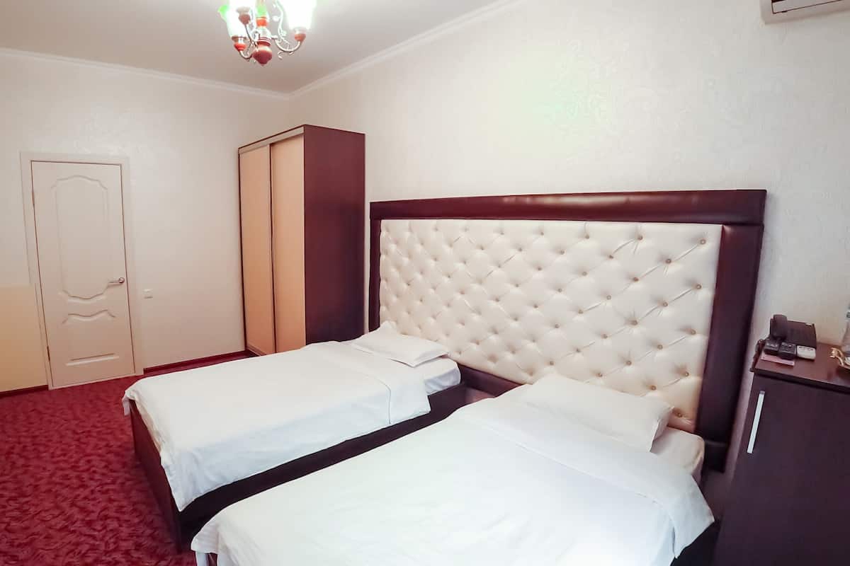 Habitación de hotel con dos camas, un armario, un televisor y una araña.
