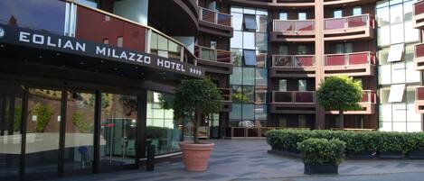 Exterior del hotel Eolian Milazzo con un diseño arquitectónico moderno, que presenta varios balcones y grandes ventanales.
