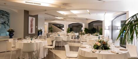 A modern dining area with round tables, white chairs, and floral centerpieces.