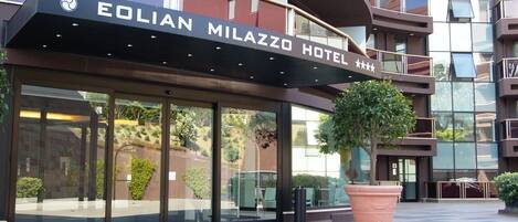 Exterior del HOTEL EOLIAN MILAZZO con un gran árbol en maceta al frente.