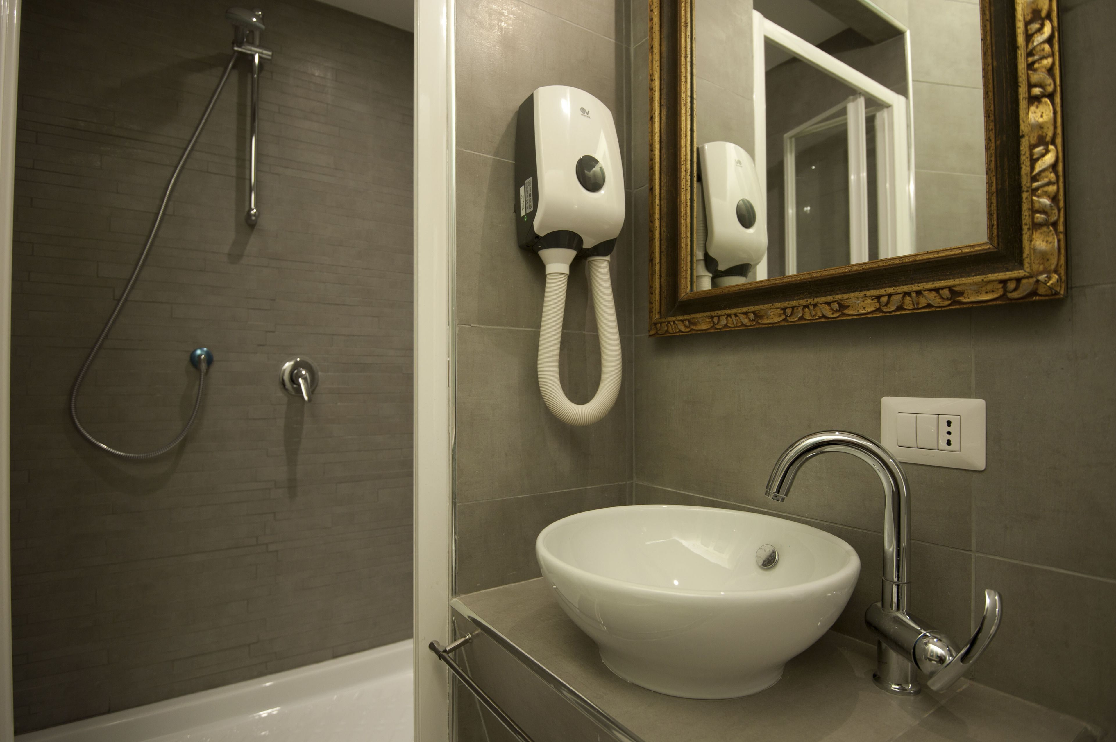 Une salle de bain équipée d’une baignoire, d’un lavabo, d’un pommeau de douche à main et d’un sèche-cheveux fixé au mur.