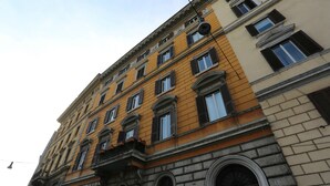 A multi-story building with a yellow facade and stone base. - Luxury on the River (Rome)