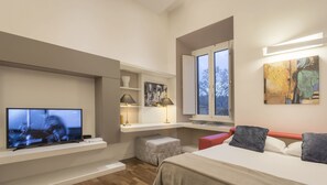 A modern hotel room with a flat-screen TV, a bed, a small seating area, and a window with a view of trees. - Luxury on the River (Rome)