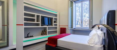 A modern bedroom with a bed, built-in shelving, a window, and a radiator.