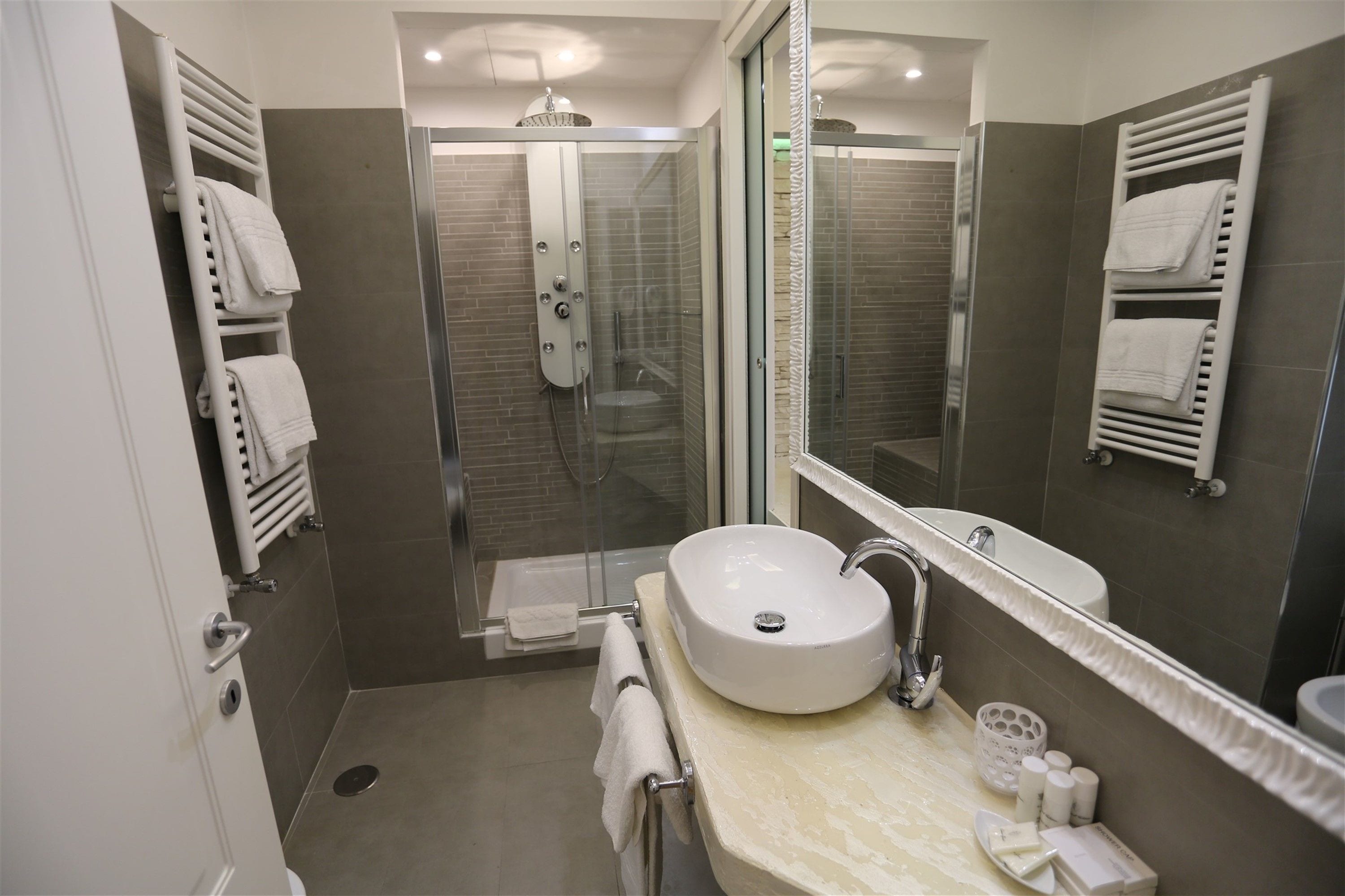 Un bagno moderno con doccia vetrata, lavandino bianco e uno specchio grande.