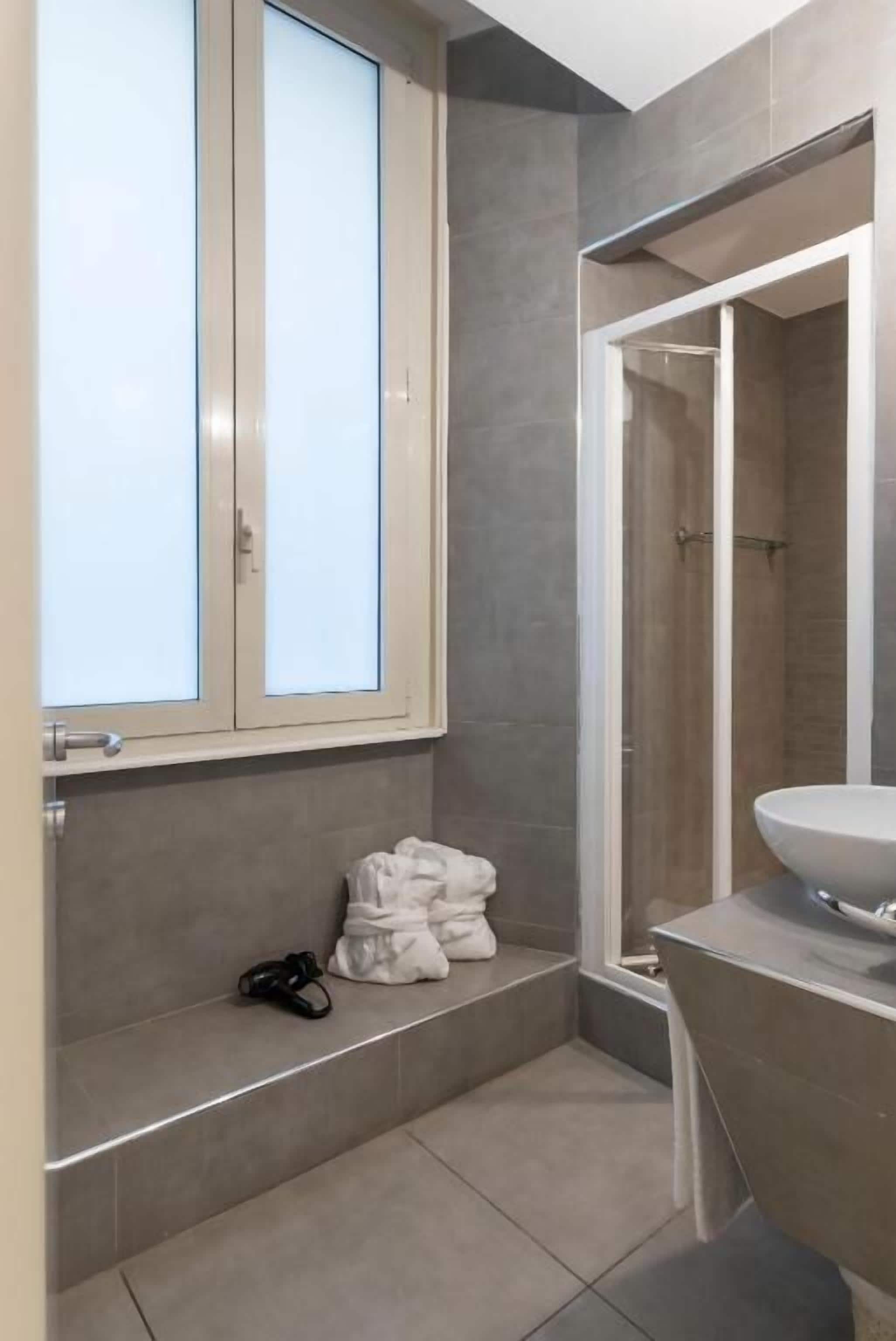 Een moderne badkamer met een grote spiegel, een witte wastafel en een douchecabine.